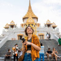 woman using smartphone standing on the background of wat traimit - travel stock pictures, royalty-free photos & images