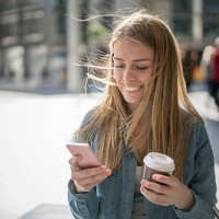 woman walking on the street texting on her phone - junk food stock pictures, royalty-free photos & images