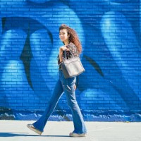 woman walking outdoors on the street. portrait of young woman with curly hair walking outdoors on the street against colorful wall. urban concept. - fashion stock pictures, royalty-free photos & images