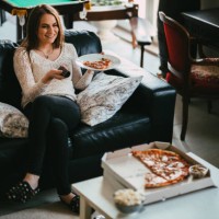 woman watching tv and and eating take-out pizza at home - junk food stock pictures, royalty-free photos & images