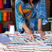 woman wearing a caftan pointing at a color card on a table of textiles - fashion photos et images de collection