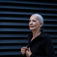 woman wearing black tracksuit top in front of black background - fashion photos et images de collection