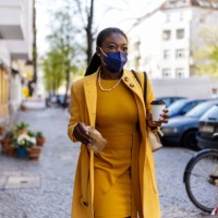 woman wearing mask walking in the city holding a take away food and coffee - junk food stock pictures, royalty-free photos & images