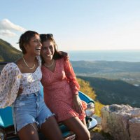 woman with arm around female friend leaning on car - travel stock pictures, royalty-free photos & images