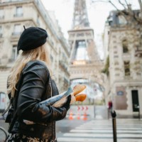 woman with blond hair, standing at a crosswalk, carrying two baguettes, eiffel tower, paris in background - food stock pictures, royalty-free photos & images