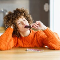 woman with eyes closed enjoying chocolate at home - food stock pictures, royalty-free photos & images