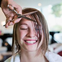 woman with eyes closed having her fringe cut off - hairstyle stock-fotos und bilder