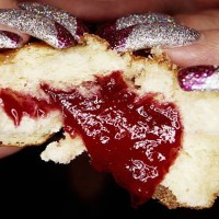 woman with long glittery nails eating jam doughnut, close-up - food stock pictures, royalty-free photos & images