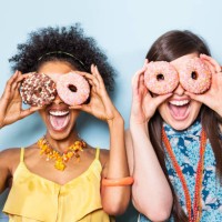 women holding doughnuts in front of eyes. - food stock pictures, royalty-free photos & images