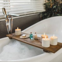 wooden tray on bath tub with burning candles, bath salt and shampoo in bottles, loofah sponge and soap - home decoration stock pictures, royalty-free photos & images