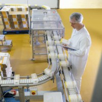 worker inspecting packed products on conveyor belt in biscuit factory - food stockfoto's en -beelden