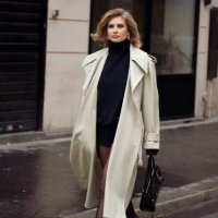 Xenia Adonts wears black tights, black loafers, black mini dress and beige trench coat outside Chloe during the Womenswear Fall/Winter 2024/2025 as...