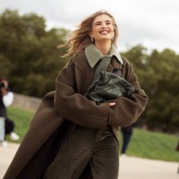 Xenia Adonts wears olive green pants, green sweater, green shirt and dark green oversized coat outside the Loewe show during Womenswear Spring/Summer...