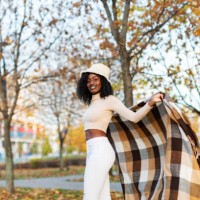 young adult black female in poncho relaxing in autumn park - fashion stock pictures, royalty-free photos & images
