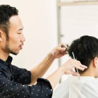 young adult male hair stylist owner cutting man's hair - hairstyle stock pictures, royalty-free photos & images