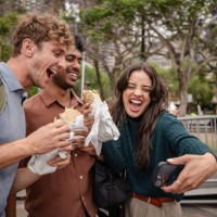 young adults enjoying food and capturing joyful moments in sydney's vibrant outdoor scene - junk food stock pictures, royalty-free photos & images