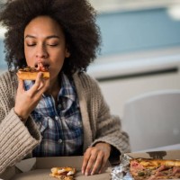 young african american woman eating pizza at home. - junk food stock pictures, royalty-free photos & images