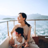 young asian mother and lovely little daughter with red sunglasses enjoying a yacht ride over nice calm sea on a summer day. looking over and relaxed at the sea. family lifestyle. enjoying outdoor fun, boat trip and sea vacati