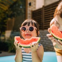young asian toddler girl refreshing with watermelon slice with her mother in backyard - food stock pictures, royalty-free photos & images