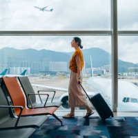 young asian woman carrying suitcase, walking by the window at airport terminal. young asian female traveller waiting for boarding at airport. business travel. travel and vacation concept - travel stock pictures, royalty-free 