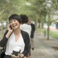 young asian woman carrying takeaway coffee and talking on the phone - junk food stock pictures, royalty-free photos & images