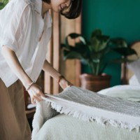 young asian woman doing her morning routine, making up her bed at home. let's get the day started - home decoration stockfoto's en -beelden