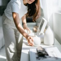 young asian woman enjoys her time at home, decorating and organising picture frames and vases on the shelf by the window - home decoration stock pictures, royalty-free photos & images