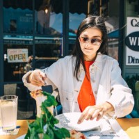 young asian woman holds a piece of pizza in outdoor summer cafe. - junk food stock pictures, royalty-free photos & images