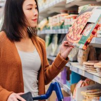 young asian woman picking up pizza in grocery store - junk food stock pictures, royalty-free photos & images