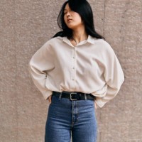 young asian woman posing with hands on hips against concrete wall - fashion stock pictures, royalty-free photos & images