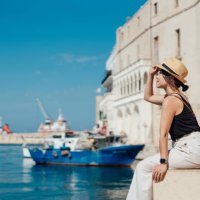 young asian woman sitting at the pier in a seaside town in italy - travel stock-fotos und bilder