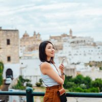 young asian woman using smart phone while overlooking the old town in ostuni, puglia, italy. - travel stockfoto's en -beelden