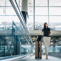young asian woman with passport carrying suitcase walking in the airport concourse - travel stock pictures, royalty-free photos & images
