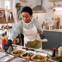 young beautiful female chef packing food in aluminum plates, getting it ready for delivery at her organic food store - food stock pictures, royalty-free photos & images