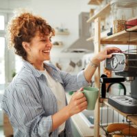 young beautiful smiling woman making coffee in a domestic kitchen - coffee stock pictures, royalty-free photos & images
