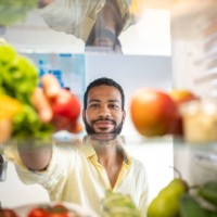 young black man grabbing food from his refrigerator - food stock pictures, royalty-free photos & images