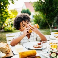 young boy eating barbecued corn on the cob - food stock pictures, royalty-free photos & images