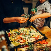 young boy sprinkling fresh herbs on vegetable dish - home decoration stock pictures, royalty-free photos & images