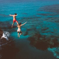 young brave divers couple jumping off cliff into ocean - travel stock pictures, royalty-free photos & images