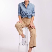 young brunette woman laughing while sitting against a gray background - fashion stock pictures, royalty-free photos & images