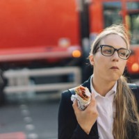 young business lady in glasses posing eating burrito on the busy street. - junk food stock pictures, royalty-free photos & images