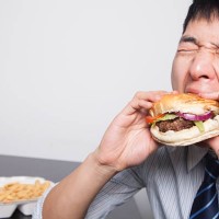 young businessman enjoying a burger - junk food stock pictures, royalty-free photos & images