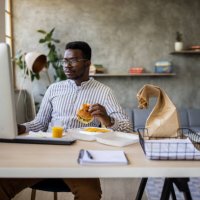 young businessman enjoying burger while taking a break from work at home office - junk food stock pictures, royalty-free photos & images
