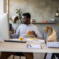 young businessman having a lunch break and eating burgers while telecommuting from home - junk food stock pictures, royalty-free photos & images