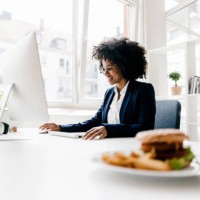 young businesswoman working with hamburger on her desk - junk food stock pictures, royalty-free photos & images