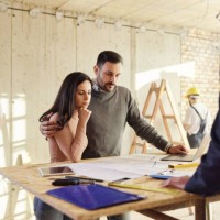 young couple analyzing housing project with their agent at construction site. - home decoration stock pictures, royalty-free photos & images
