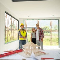young couple and their agent examining blueprints at construction site. - home decoration stock pictures, royalty-free photos & images