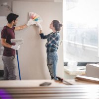 young couple choosing the right color for their wall while renovating apartment. - home decoration stock pictures, royalty-free photos & images