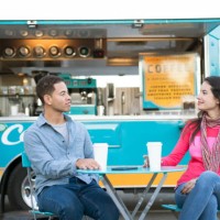 young couple drinking coffee in front of a food truck - junk food stock pictures, royalty-free photos & images