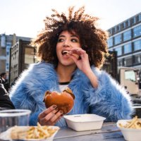 young couple eating burger and chips outdoors - junk food stock pictures, royalty-free photos & images